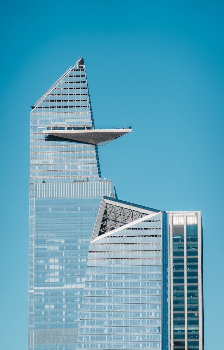 Modern skyscrapers reach towards a clear, blue sky.